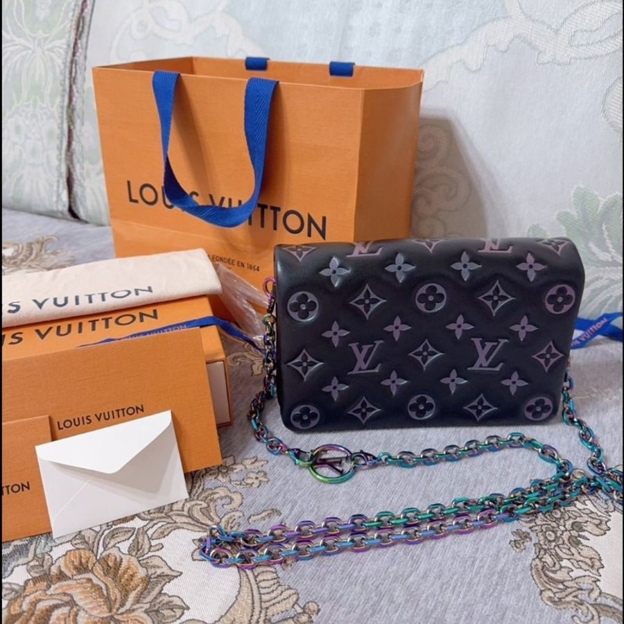 這款包包是路易威登(Louis Vuitton)Twist MM 系列,具有標誌性的LV旋轉鎖扣和Monogram圖案。從設計特徵和炫彩金屬鏈條來看,這款包可能是Twist MM Rainbow Hardware特別版,該系列以特殊的虹彩金屬鏈條和經典黑色Epi皮革聞名,並保留了品牌經典的奢華感與現代設計元素。-2