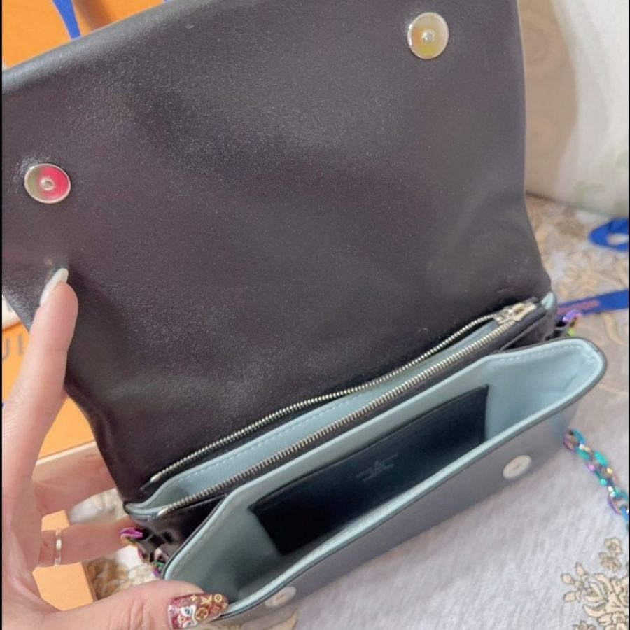 這款包包是路易威登(Louis Vuitton)Twist MM 系列,具有標誌性的LV旋轉鎖扣和Monogram圖案。從設計特徵和炫彩金屬鏈條來看,這款包可能是Twist MM Rainbow Hardware特別版,該系列以特殊的虹彩金屬鏈條和經典黑色Epi皮革聞名,並保留了品牌經典的奢華感與現代設計元素。-14