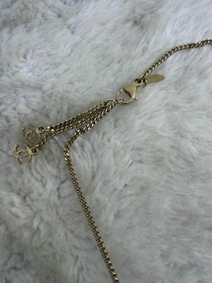 這條 Chanel 品牌項鍊以金屬色細鍊搭配由紫色寶石與經典雙 C Logo 組成的花卉狀墜飾。-5