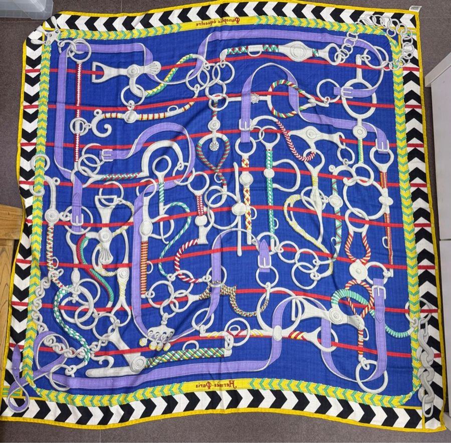 這是一條 Hermès Panoplie Equestre 絲巾，以其藍色為底色和複雜的馬具圖案為特色-1
