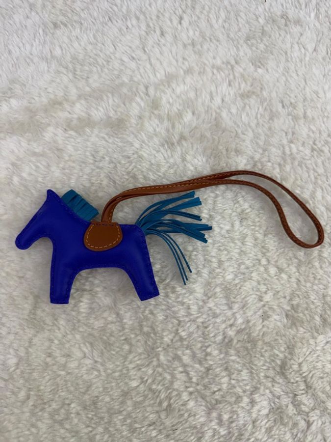 這是一個藍色的 Hermès Rodeo 皮革包包吊飾,採用經典的馬形設計,配有深藍色馬身、淺藍色鬃毛和尾巴,以及褐色馬鞍-1