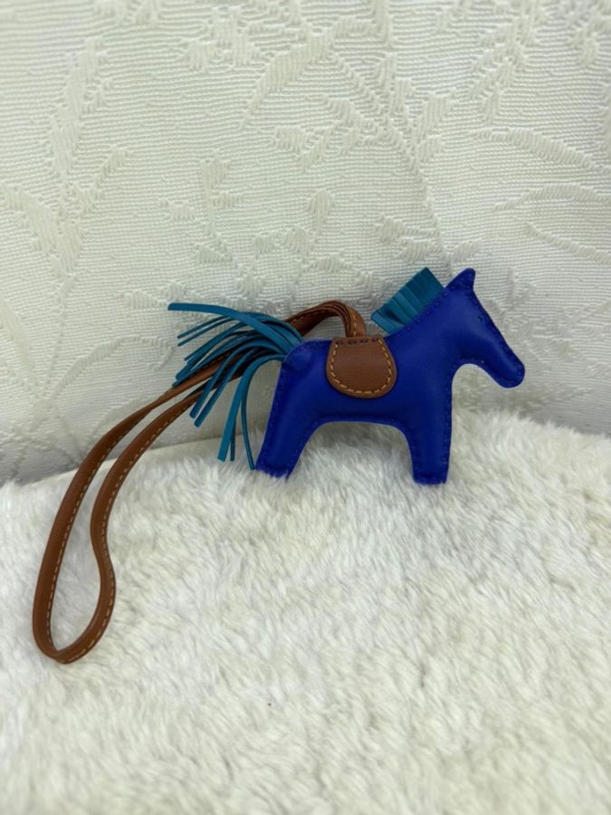 這是一個藍色的 Hermès Rodeo 皮革包包吊飾,採用經典的馬形設計,配有深藍色馬身、淺藍色鬃毛和尾巴,以及褐色馬鞍-2