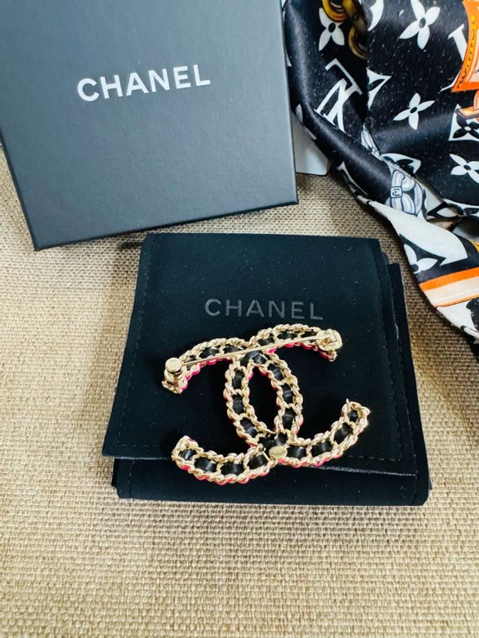Chanel 皮穿鏈雙C胸針，經典款，黑色小牛皮穿金色鏈條，背面可以看到CHANEL字樣的底扣。-1